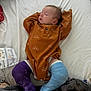baby, sleeping, cast, leg_cast, orange_outfit, bed, blanket, diaper, infant, resting, soft_fabric, patterned_clothing, purple_cast, blue_cast, newborn, cute, child, indoors, comfort, relaxation