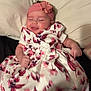 Vanessa is registered to the contest to win money with this photo: baby, child, infant, smiling, floral_dress, headband, flower, bed, pillow, happy, cute, lying_down, skin, hand, foot, indoors, person, portrait, clothing, sleepy