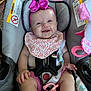 baby, car_seat, pink_bow, bib, smile, infant, child, seat_belt, pacifier, clothing, toy, happy, cute, headband, indoor, person, baby_accessory, fabric, hand, foot