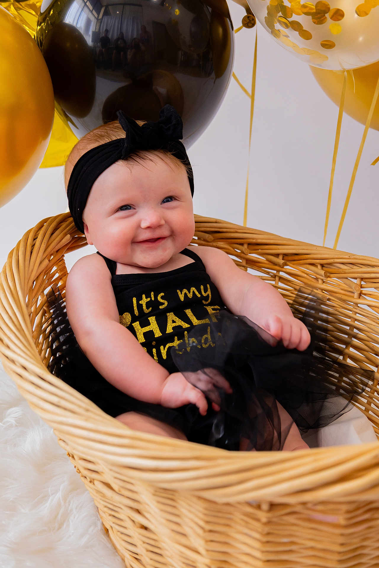 Paisley joined the competition — help win amazing prizes! baby, infant, basket, balloons, black_headband, black_outfit, gold_text, smiling, celebration, half_birthday, cute, happy, indoor, wicker, tulle_skirt, headband, child, portrait, decorations, soft_fur_rug