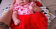 Ruby is registered to the contest to win money with this photo: baby, bed, blanket, bow, child, clothing, cushion, cute, hand, headband, indoor, infant, patterned_cushion, person, pink_top, portrait, red_skirt, resting, skin, tattoo