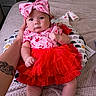 baby, infant, child, red_skirt, pink_top, headband, bow, tattoo, hand, bed, blanket, cushion, patterned_cushion, indoor, cute, portrait, clothing, person, skin, resting