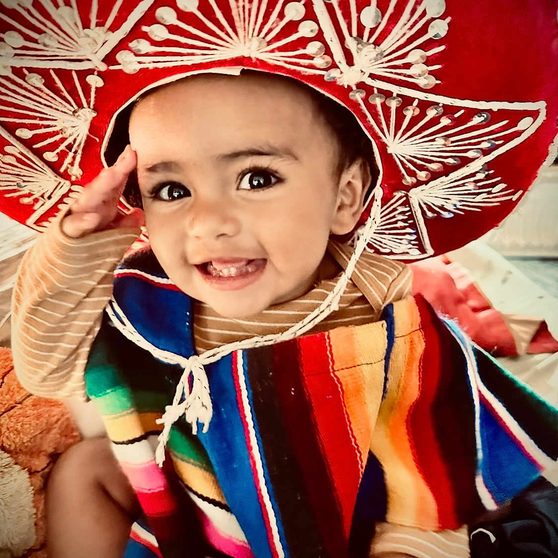 Emmanuel Mendoza is registered to the contest to win money with this photo: baby, bright_colors, candid, celebration, cheerful, child, clothing, colorful_poncho, cute, face, happy, hat, indoor, person, playful, portrait, saluting, smiling, sombrero, toddler