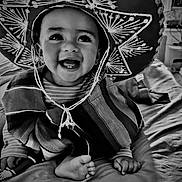 Emmanuel Mendoza joined the competition — help win amazing prizes! baby, child, smiling, sombrero, hat, poncho, striped_clothing, bed, foot, hand, indoor, black_and_white, portrait, happy, cute, person, cozy, expression, infant, clothing