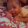 Kai'Lani is registered to the contest to win money with this photo: baby, blanket, child, clothing, cute, face, floral_pattern, hair_clips, hands, happy, indoors, infant, lying_down, manicure, person, portrait, skin, smile, toddler, young