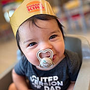 Jackson joined the competition — help win amazing prizes! baby, black_hair, blurred_background, burger_king_crown, child, clothing, cute, face, food_court, happy, headwear, high_chair, indoor, infant, pacifier, person, restaurant, sitting, smiling, toddler