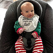 Amaury a rejoint le concours — aidez-le/la à gagner de superbes lots ! baby, infant, smiling, bib, clothing, striped_pants, green_sweater, baby_seat, cushion, indoor, floor_tiles, wooden_cabinet, happy, face, person, child, cute, portrait, sitting, baby_bib