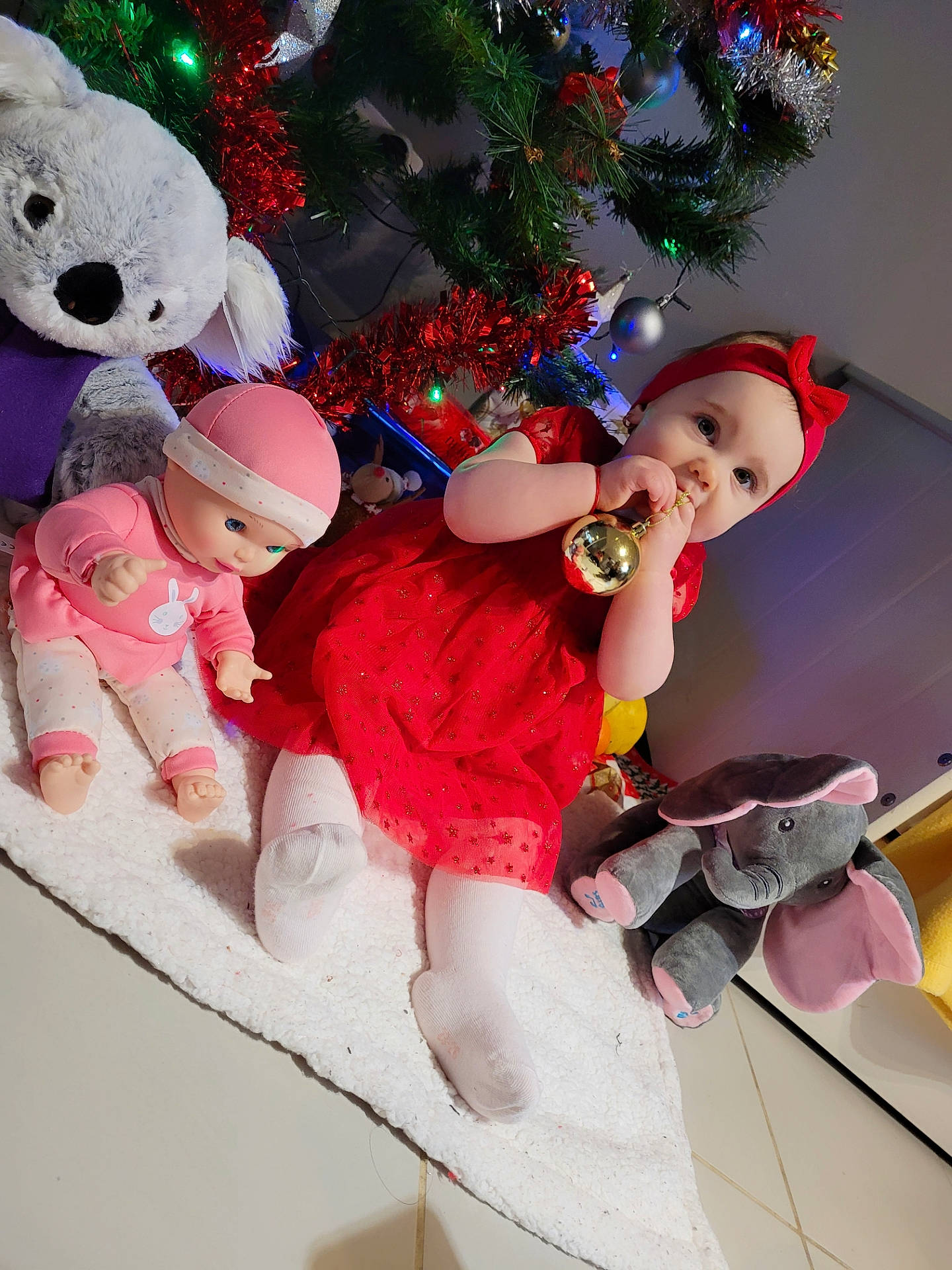 Isabelle a rejoint le concours — aidez-le/la à gagner de superbes lots ! baby, christmas, christmas_decoration, christmas_ornament, christmas_tree, event, facial_expression, fun, happy, headwear, holiday, holiday_ornament, human_body, lap, ornament, person, pink, plant, santa_claus, toddler