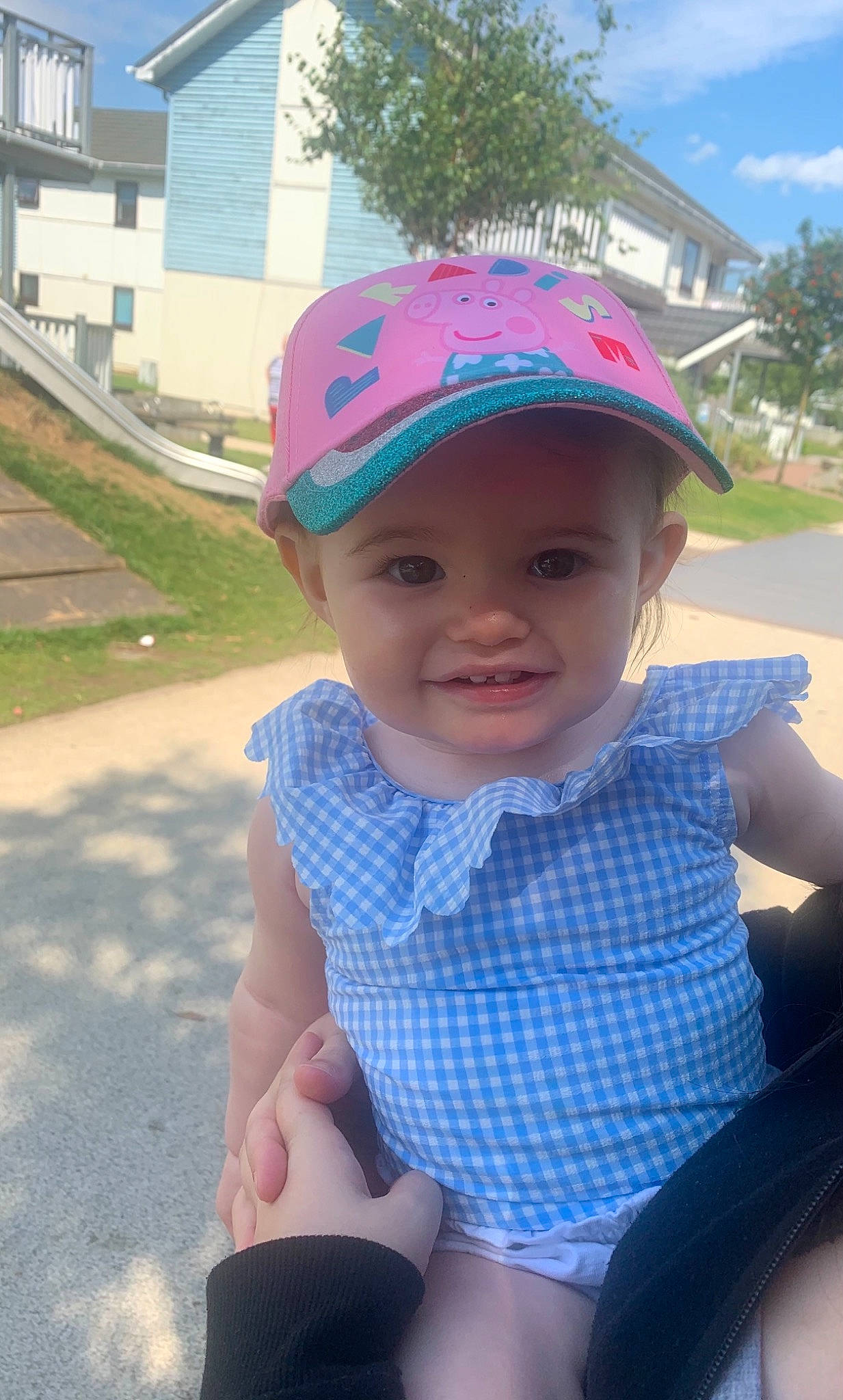 Maya is registered to the contest to win money with this photo: baby_toddler_clothing, baseball_cap, blue, cap, chin, cool, eye, grass, happy, hat, headwear, human_body, lip, person, pink, plant, public_space, skin, smile, t_shirt