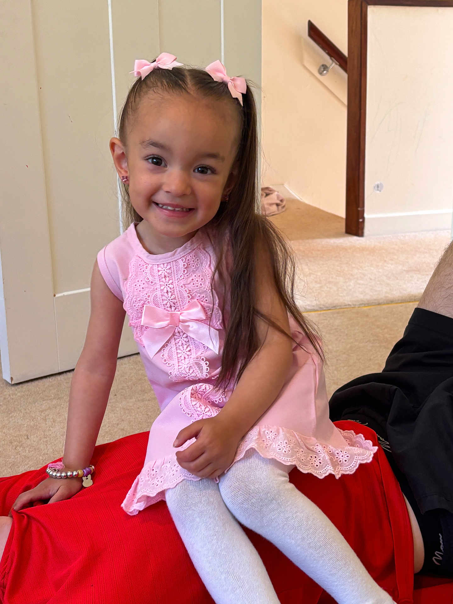 Paisley is registered to the contest to win money with this photo: child, girl, smile, pink_dress, hair_bows, bracelet, white_tights, indoor, carpet, wall, staircase, person, sitting, happy, playful, casual, family, home, portrait, candid