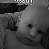 baby, black_and_white, blanket, child, clock, close_up, couch, digital_display, eyes, face, grayscale, home, indoor, infant, lock_screen, lying_down, photography, portrait, serious, soft_furnishings
