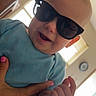 Jacob joined the competition — help win amazing prizes! baby, child, infant, sunglasses, smiling, happy, portrait, being_held, indoor, living_room, blue_shirt, face, head, hands, adult_hand, window, daylight, home, playful, funny
