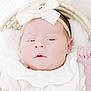 baby, newborn, infant, headband, bow, white_clothing, basket, blanket, sleepy, cozy, soft, cute, portrait, closeup, child, face, hand, peaceful, indoors, resting