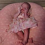 baby, infant, pink, dress, cushion, flower_pattern, sleeping, hands, feet, soft, fabric, cute, child, newborn, lying_down, bedroom, cozy, portrait, pale_skin, peaceful