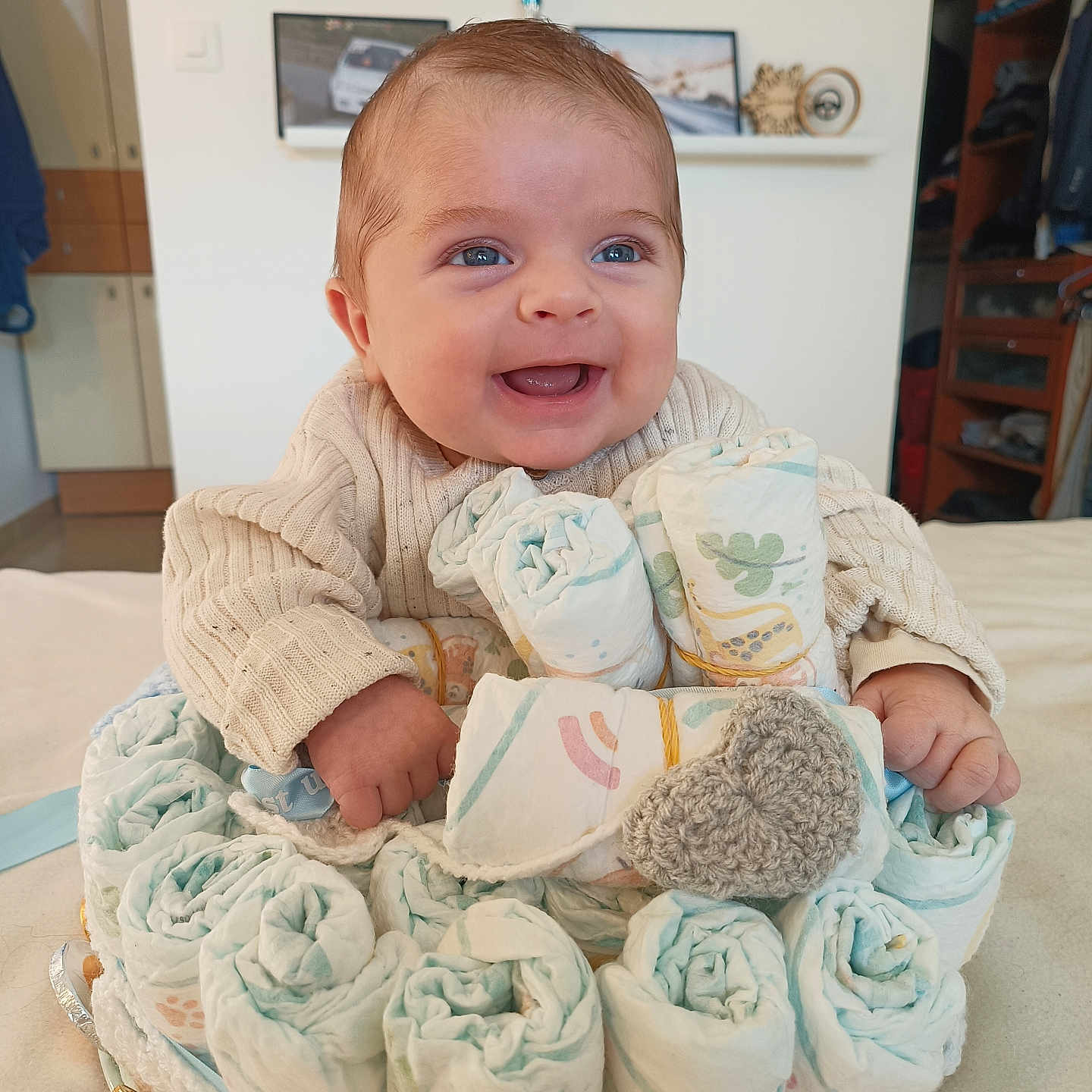 Lino a rejoint le concours — aidez-le/la à gagner de superbes lots ! baby, background, blue_eyes, celebration, child, creative, crocheted_heart, cute, diaper_cake, diapers, face, hand, happy, home, indoor, infant, portrait, smiling, soft_lighting, sweater