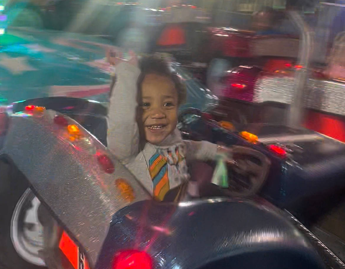 Jalen is registered to the contest to win money with this photo: auto_part, automotive_design, automotive_exterior, automotive_lighting, automotive_tire, black_hair, bumper, car, fun, hood, joy, mode_of_transport, motor_vehicle, person, personal_luxury_car, smile, steering_wheel, tire, toy, vehicle