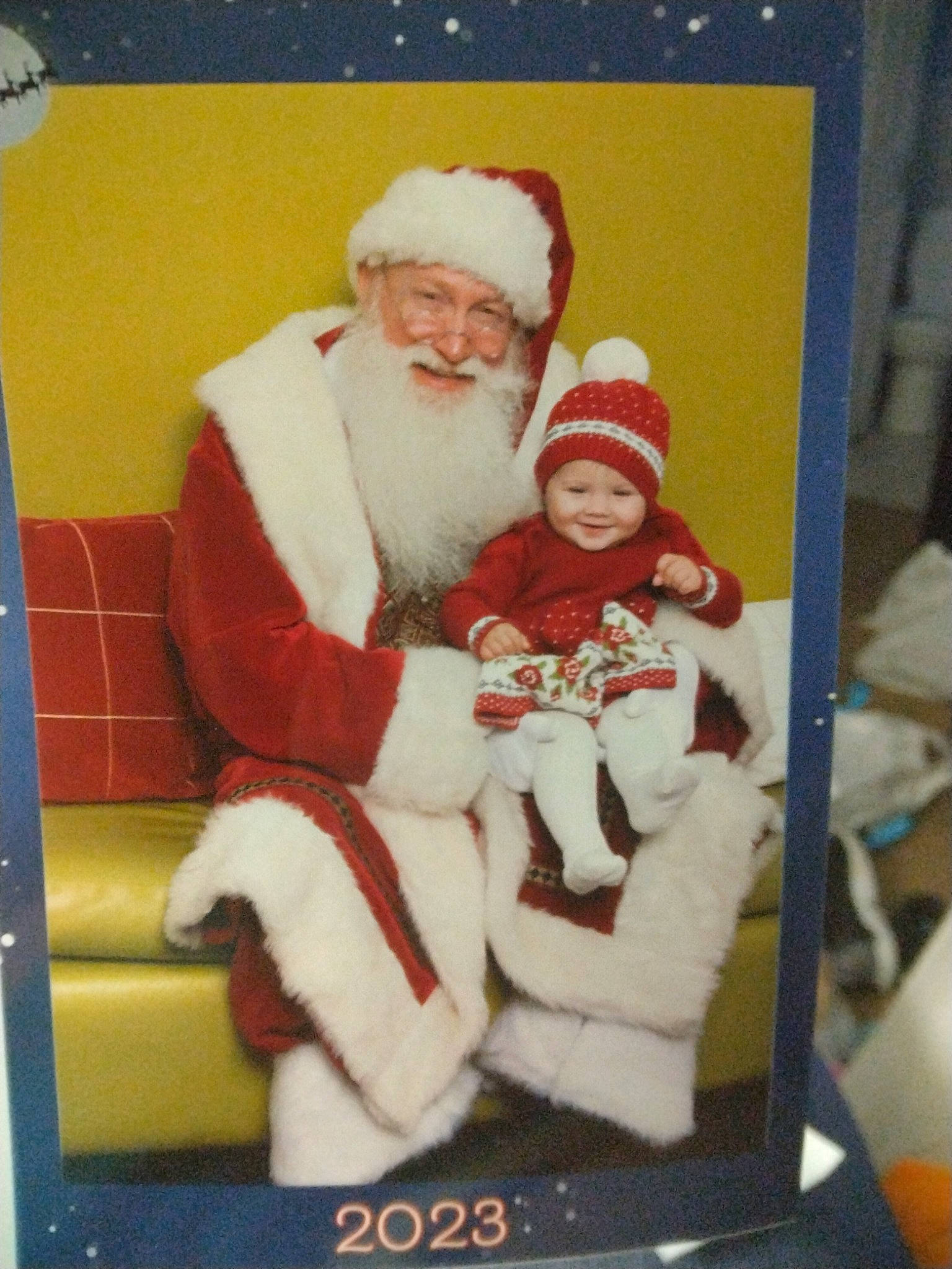 Rosalee is registered to the contest to win money with this photo: baby, beard, chair, child, christmas, christmas_eve, event, fictional_character, fur, happy, hat, headwear, holiday, interior_design, joy, lap, person, santa_claus, sitting, smile