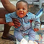 baby, child, denim_shirt, pants, socks, indoor, glass_table, person, hand, floor, tablet, adult, smiling, seated, casual_clothing, living_room, footwear, toy, expression, furniture