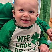 Roman joined the competition — help win amazing prizes! baby, infant, toddler, smiling, face, eyes, teeth, cheeks, onesie, green_clothing, shamrock, st_patricks, portrait, indoor, sitting, hands, party_streamers, cute, happy, clothing