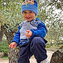 Alessio a rejoint le concours — aidez-le/la à gagner de superbes lots ! blue_clothing, child, daylight, footwear, greenery, happy, hat, jacket, leaves, nature, outdoor, pants, person, playful, portrait, shoes, smiling, toddler, tree, young_child