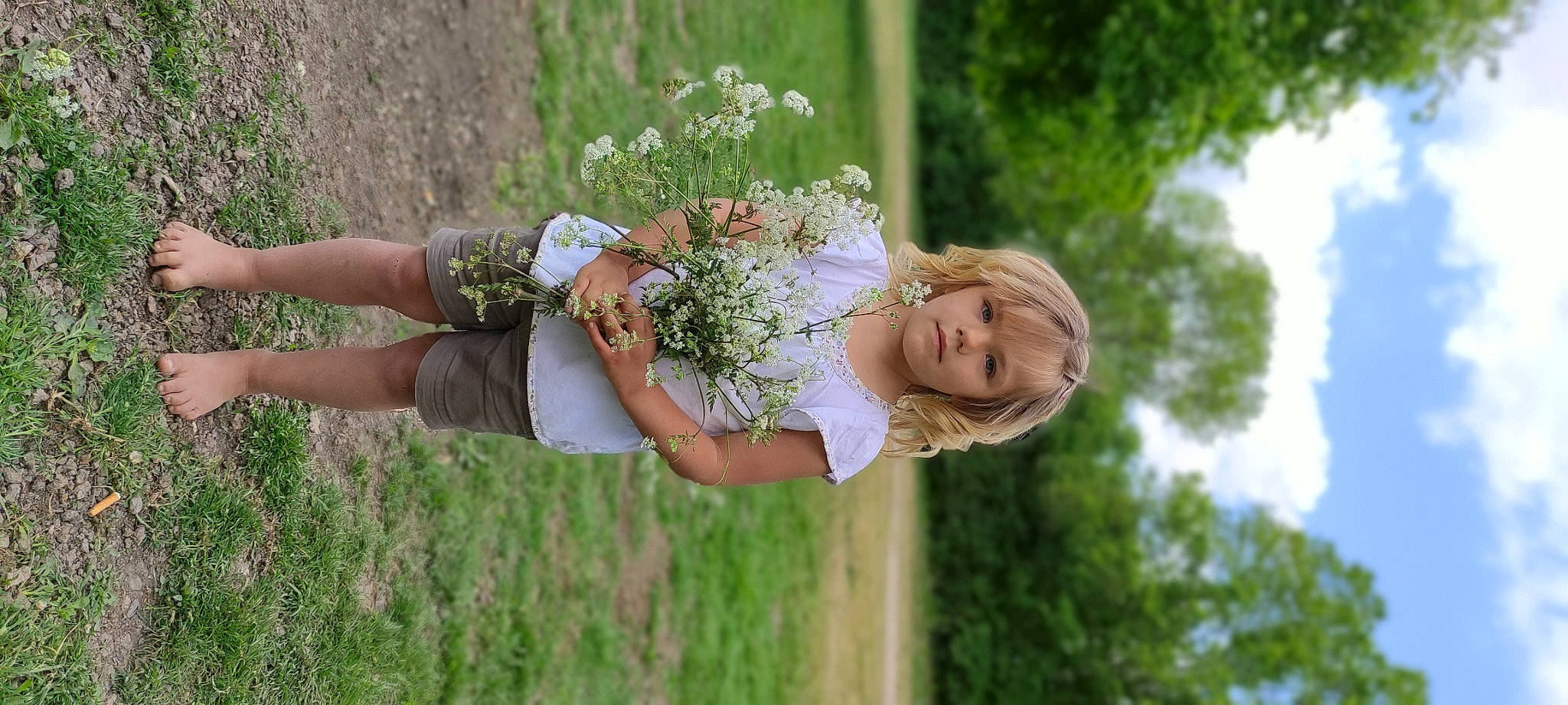Ënoline a rejoint le concours — aidez-le/la à gagner de superbes lots ! baby, blond, bridal_clothing, dress, flower, flower_arranging, gesture, grass, grass_family, happy, lawn, meadow, people_in_nature, person, petal, plant, rose_family, sunlight, toddler, tree
