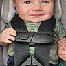 baby, child, car_seat, seatbelt, smile, blue_eyes, camouflage_clothing, hair, infant, safety_harness, cute, portrait, baby_clothes, indoor, seat, headrest, hand, red_button, pacifier, happy