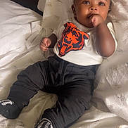 Khasson joined the competition — help win amazing prizes! baby, infant, child, bed, blanket, pillow, clothing, shirt, pants, socks, face, hand, thumb, cute, indoors, portrait, relaxed, lying_down, black_pants, white_shirt