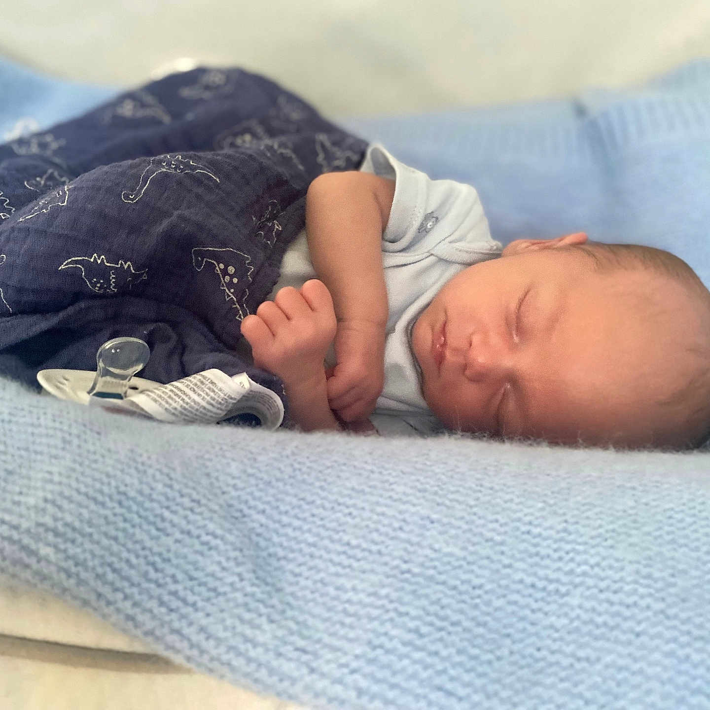 Enzo-John joined the competition — help win amazing prizes! baby, blanket, blue_blanket, child, cozy, cute, dinosaur_print, face, hand, indoors, infant, knitted_blanket, newborn, pacifier, peaceful, portrait, resting, sleeping, soft_texture, wrapped