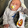 baby, pacifier, blanket, onesie, striped_clothing, blue_star, hand, infant, sleepy, face, portrait, cozy, soft_texture, child, newborn, cute, indoors, resting, human, comfort