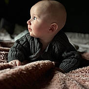 Jace joined the competition — help win amazing prizes! baby, infant, child, knitted_sweater, blanket, soft_texture, portrait, side_profile, curious, indoors, warm_lighting, cozy, cute, young_child, toddler, person, face, hand, sleeping_area, resting