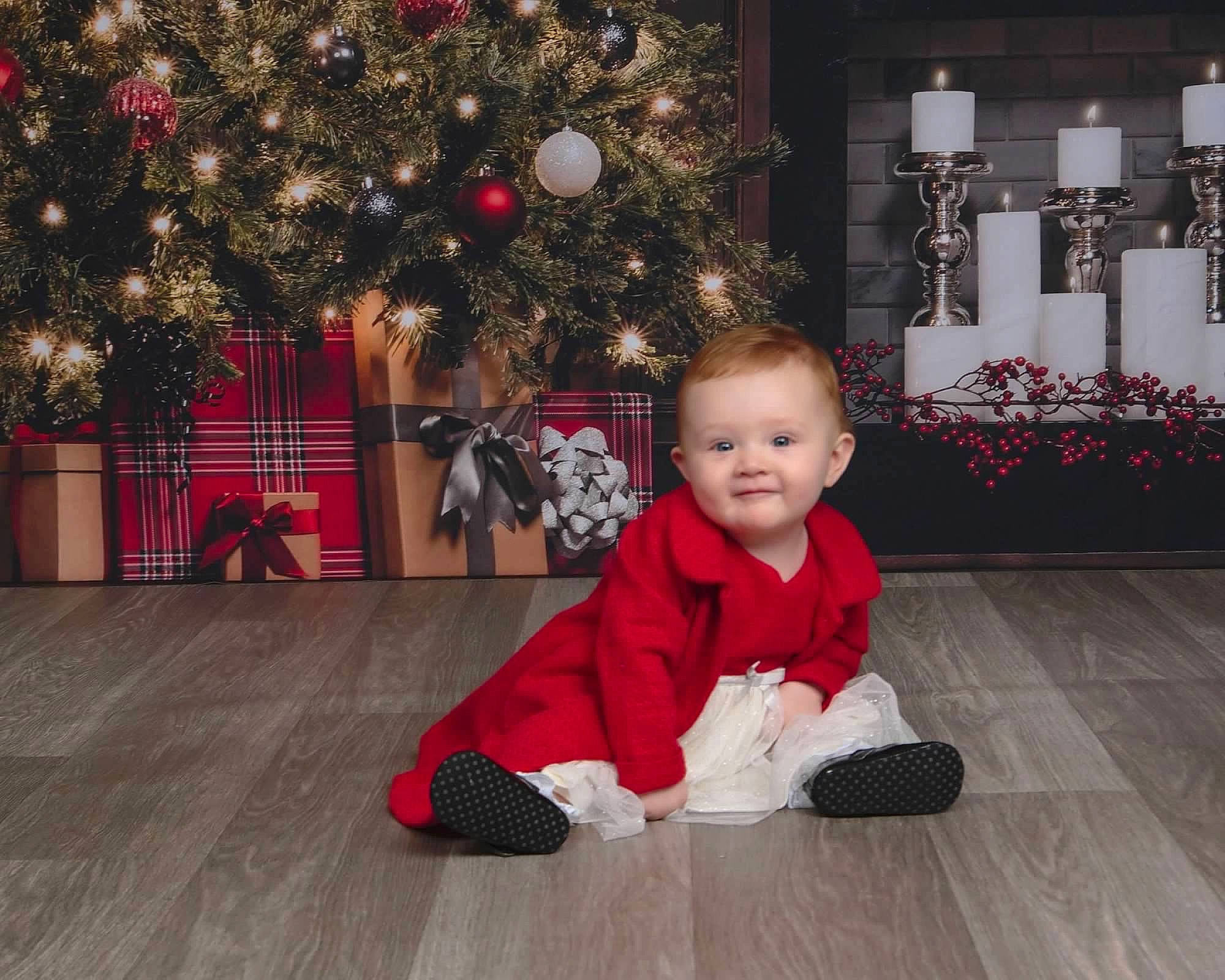 Evelyn joined the competition — help win amazing prizes! baby, baby_toddler_clothing, christmas_decoration, christmas_ornament, christmas_tree, event, floor, flooring, fun, happy, hardwood, holiday, holiday_ornament, joy, ornament, person, plant, smile, standing, toddler