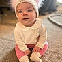 baby, carpet, child, cozy, cute, face, hat, headwear, indoor, infant, person, pink_leggings, pom_poms, portrait, sitting, smiling, socks, soft_lighting, white_clothing, young_child