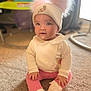 adorable, baby, carpet, child, clothing, cute, floor, hat, headwear, indoor, infant, person, pink_leggings, pom_poms, portrait, sitting, smiling, soft_lighting, white_top, young_child