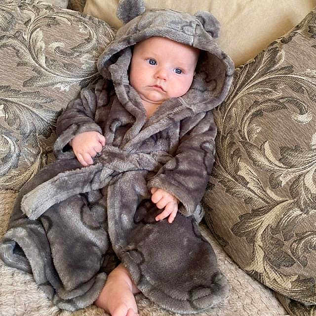 Tommy joined the competition — help win amazing prizes! baby, child, robe, hood, plush, couch, pillow, indoor, blue_eyes, soft_texture, cute, portrait, infant, cozy, comfortable, seated, home, fabric, expression, wearing