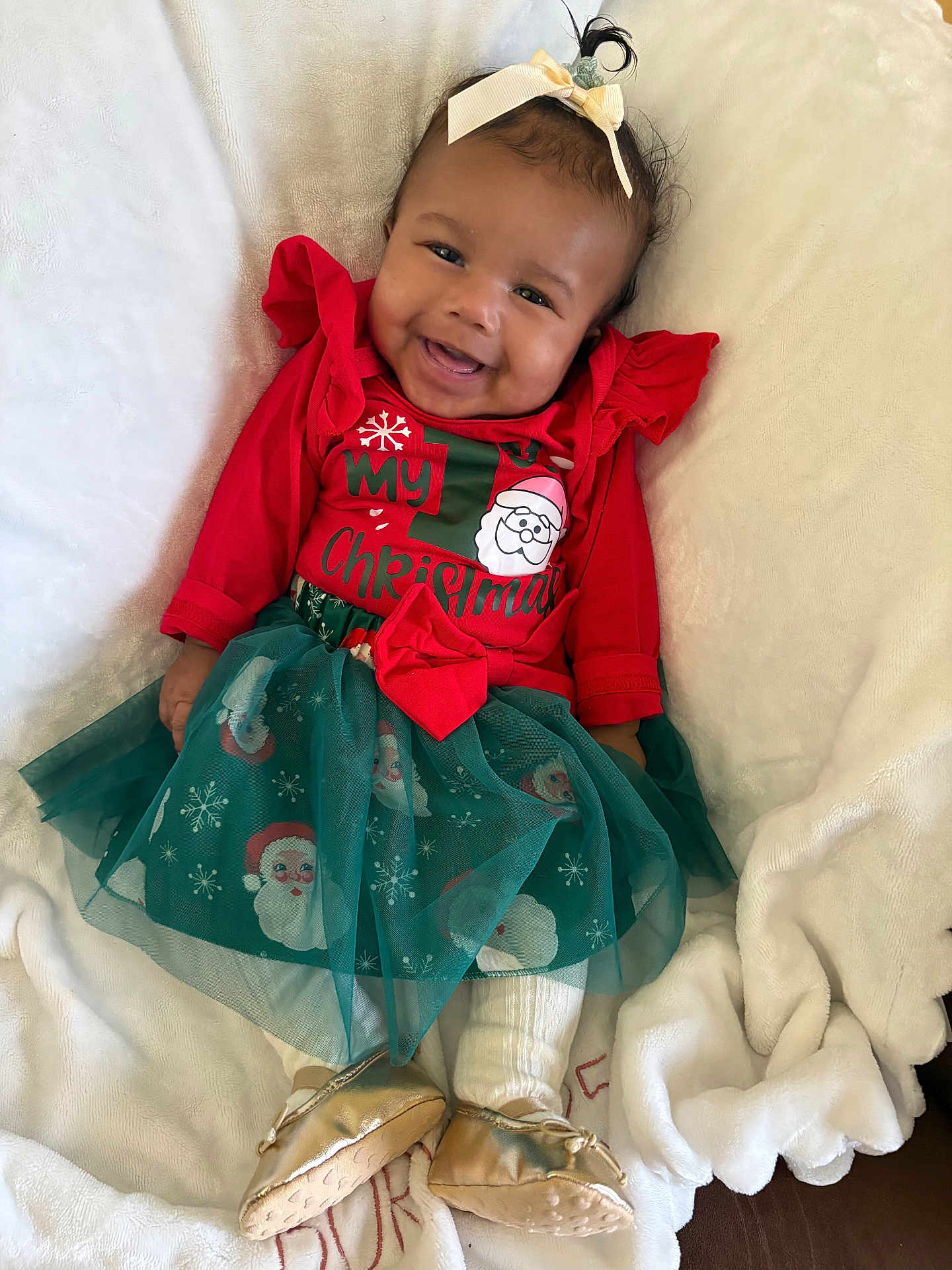Zalani is registered to the contest to win money with this photo: baby, blanket, bow, child, christmas, cute, dress, footwear, gold_shoes, green_skirt, happy, headband, holiday, indoor, infant, portrait, red_clothing, santa_claus, smiling, white_blanket