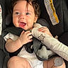 Athena joined the competition — help win amazing prizes! baby, child, car_seat, smiling, happy, curly_hair, toy, infant, seatbelt, white_clothing, cute, safety, closeup, face, skin, small_hands, indoors, car, child_safety, expression