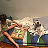 Poisson Ruby participe au concours pour gagner de l'argent avec cette photo : animal, bed, blanket, board_game, casual, child, comfort, couch, curly_hair, dog, furniture, game_piece, human, indoor, pet, pillow, playing, relaxed, resting, striped