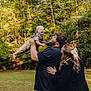 family, child, toddler, man, woman, outdoor, park, greenery, smile, happy, beard, casual_clothing, hair_bow, nature, trees, grass, playful, joy, parenthood, affection