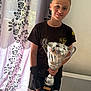 Serena participe au concours pour gagner de l'argent avec cette photo : child, trophy, sportswear, smile, indoor, curtain, radiator, black_shirt, shorts, wrist_brace, happy, young_athlete, award, celebration, portrait, person, standing, light, victory, achievement