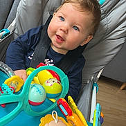 Iréne participe au concours pour gagner de l'argent avec cette photo : baby, baby_seat, blue_eyes, blue_tray, casual_clothing, child, child_in_seat, closeup, colorful_toys, curious, gray_seat, happy_baby, indoors, plastic_toys, playtime, seat_belt, smiling, toy, wooden_floor, young_child