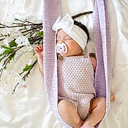 True is registered to the contest to win money with this photo: baby, sleeping, pacifier, headband, bow, knit, lavender, hammock, flower, white, soft, cute, infant, peaceful, cozy, portrait, newborn, blanket, delicate, resting