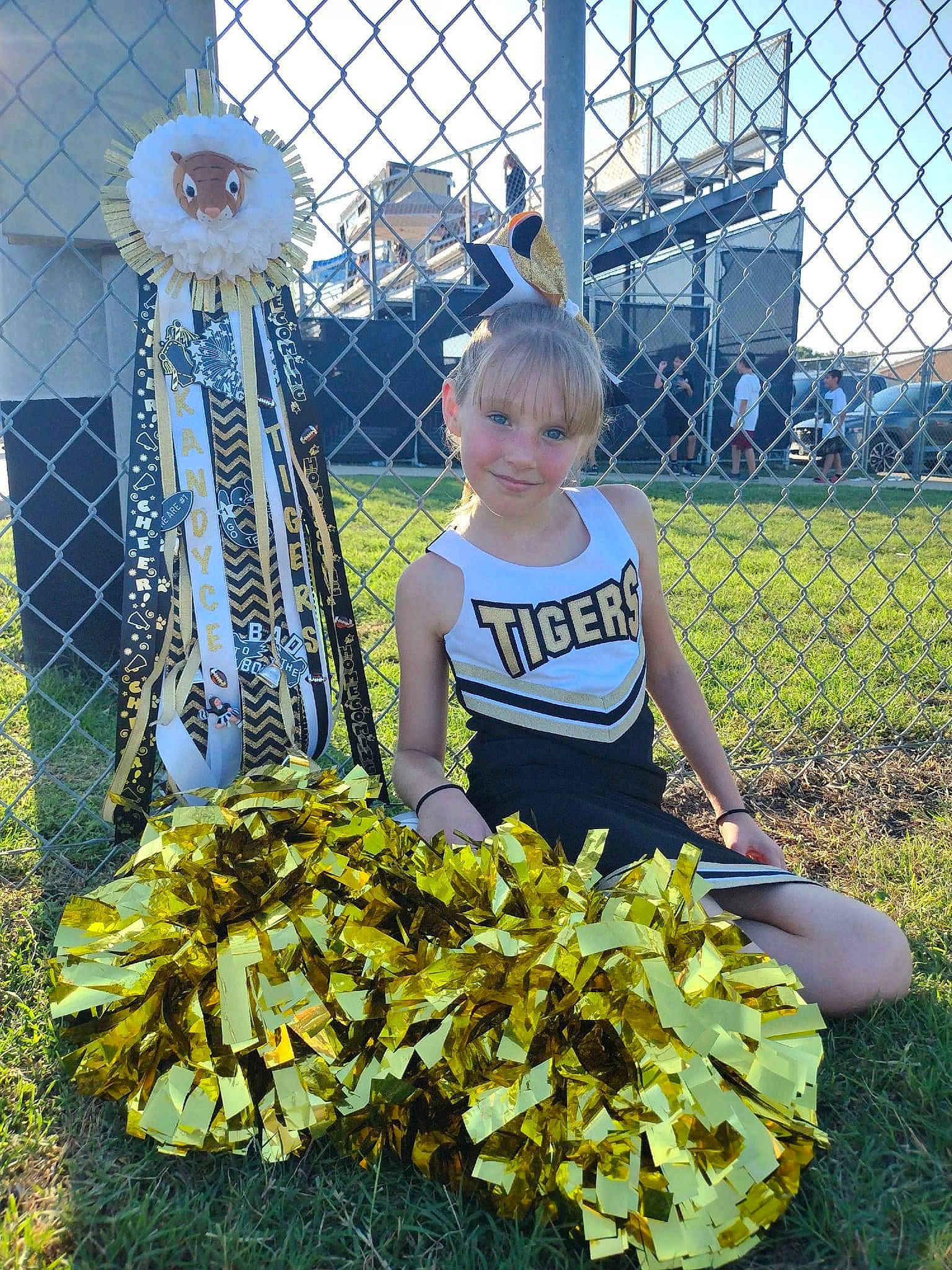 Kandyce is registered to the contest to win money with this photo: cheerleading_uniform, event, fence, flower, fun, garden, grass, human_body, joy, leisure, people_in_nature, person, plant, pole, sky, smile, spring, sunflower, t_shirt, toddler