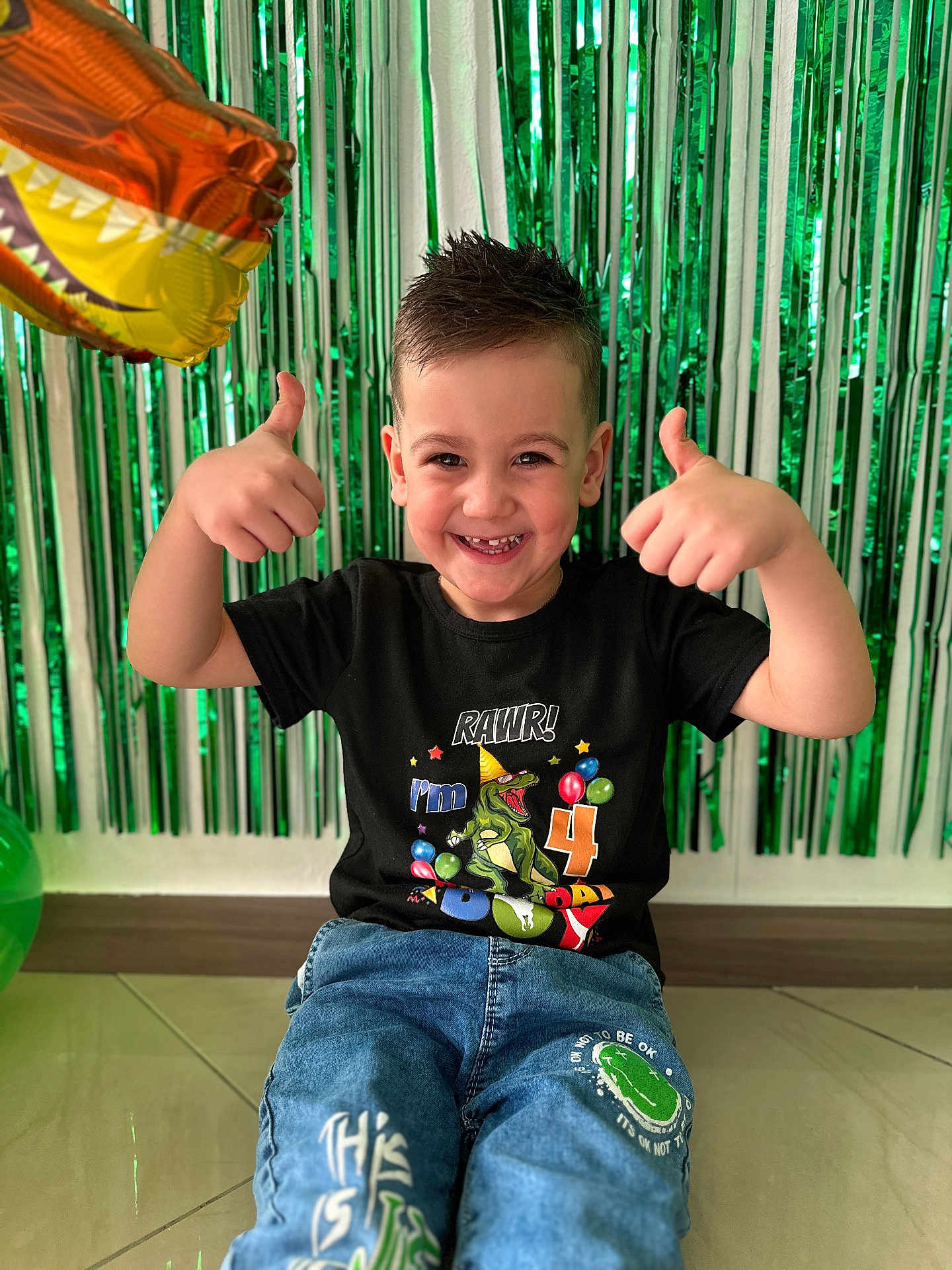 Berintan Matei participe au concours pour gagner de l'argent avec cette photo : balloon, birthday, boy, casual_clothing, celebration, child, cute, dinosaur, floor, green_streamers, hair, happy, indoor, jeans, party, portrait, smiling, thumbs_up, tshirt, young