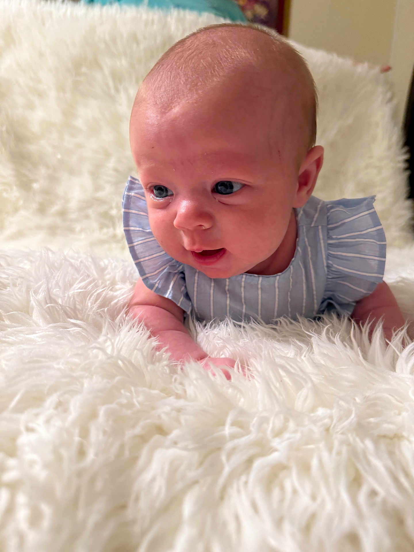 Lilah is registered to the contest to win money with this photo: baby, infant, blue_eyes, curious, fluffy_blanket, striped_clothing, ruffled_sleeves, cute, lying_down, soft_texture, closeup, portrait, child, indoor, skin, head, hands, newborn, young_child, expression