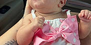 Lilah is registered to the contest to win money with this photo: baby, infant, pink_bow, polka_dot, headband, tattoo, car_interior, child, cute, clothing, person, holding, seat, skin, arm, legs, cute_outfit, pink, white, portrait