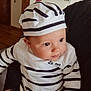 baby, infant, child, sailor_hat, striped_shirt, navy_stripes, blue_jeans, held_in_arms, portrait, indoor, wooden_floor, photo_collage, wall_frame, bracelet, rosy_cheeks, big_eyes, cute_expression, casual_clothing, family_photo, heart_sticker