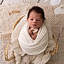 baby, basket, blanket, cream, cute, decorative_blanket, face, hands, heart_shaped_object, indoors, infant, newborn, peaceful, portrait, resting, sleepy, soft_texture, white, wooden_floor, wrapped