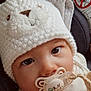 Ezio a rejoint le concours — aidez-le/la à gagner de superbes lots ! baby, infant, pacifier, knit_hat, white_hat, pom_pom, car_seat, close_up, portrait, big_eyes, cute, adorable, pacifier_clip, neutral_expression, cozy, soft_texture, blanket, infant_clothing, heart_graphic, indoors