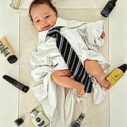 Ezio a rejoint le concours — aidez-le/la à gagner de superbes lots ! baby, infant, tie, striped_tie, white_shirt, towel, watch, cologne, perfume_bottle, skincare_tube, jar, electric_trimmer, clipper_attachment, foot, legs, smile, portrait, props, flat_lay, grooming_products