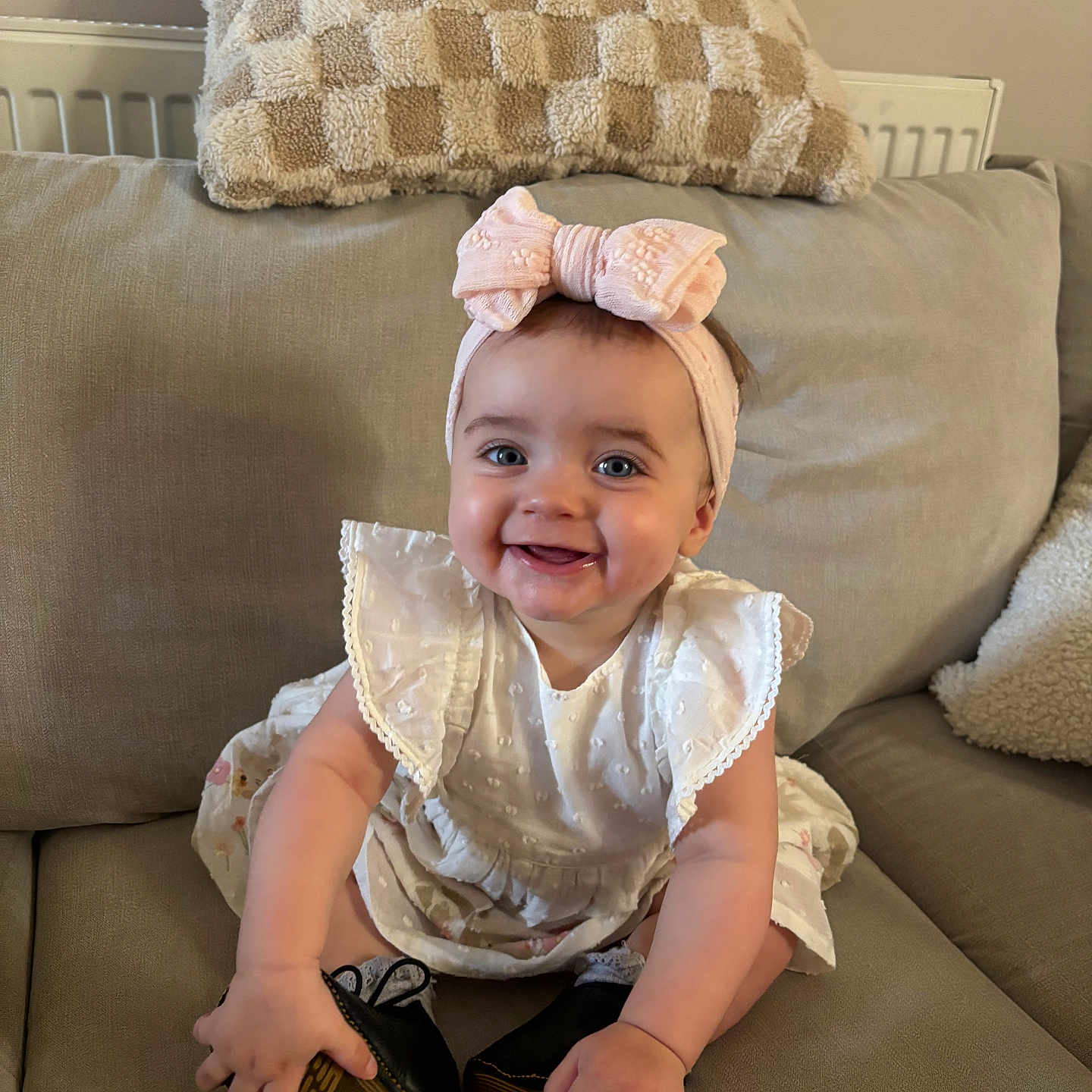Willow joined the competition — help win amazing prizes! baby, beige_couch, black_shoes, bow, checkered_pillow, child, couch, cute, dress, happy, headband, indoors, infant, person, pillow, portrait, shoes, sitting, smiling, white_dress